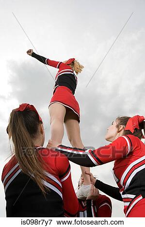 Stock Photo - Cheerleaders holding girl up. Fotosearch