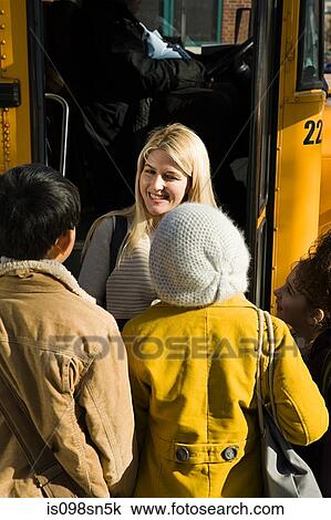 Stock Image - Children and teacher by school bus. Fotosearch