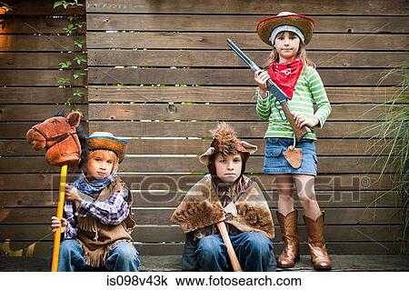 Stock Image - Children dressed up as cowgirl, bear and cowboy. Fotosearch