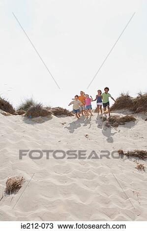 Stock Image - Children running down a dune. Fotosearch
