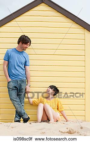 Stock Image - Couple by a beach hut. Fotosearch