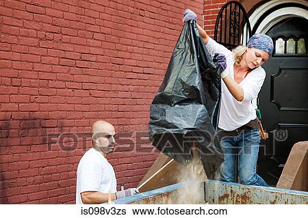Stock Photograph - Couple filling skip with rubble. Fotosearch