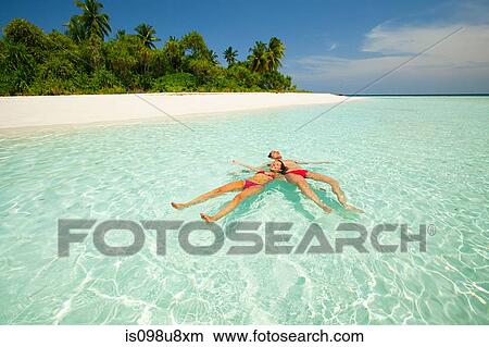 Couple floating in the sea, Baughagello Island, South Huvadhu Atoll, Maldives View Large Photo Image Picture - Couple floating in the sea, Baughagello Island, South Huvadhu Atoll, Maldives. Fotosearch