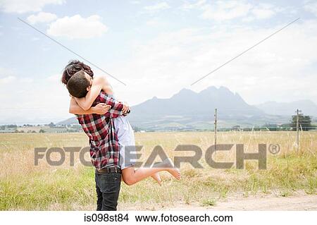 Picture - Couple hugging in field. Fotosearch