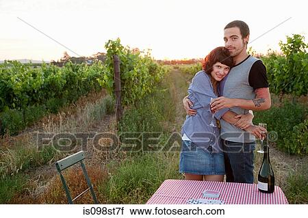 Stock Image - Couple in a field with table and wine. Fotosearch