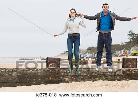 Couple jumping off fence at beach View Large Photo Image Stock Photo - Couple jumping off fence at beach. Fotosearch