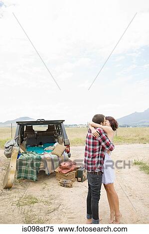 Stock Photography - Couple kissing by suv. Fotosearch