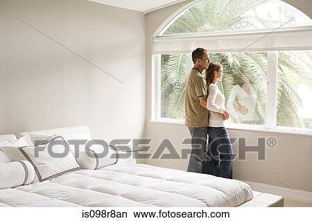 Picture - Couple looking out of bedroom window. Fotosearch