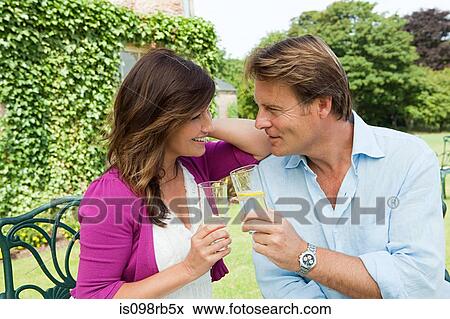 Stock Photo - Couple outdoors toasting with drinks. Fotosearch