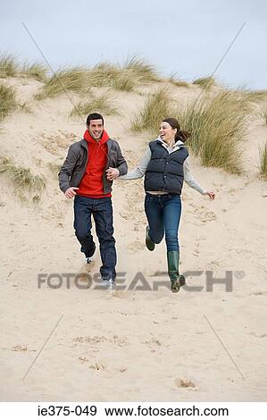 Couple running on a sandy beach View Large Photo Image Stock Photo - Couple running on a sandy beach. Fotosearch