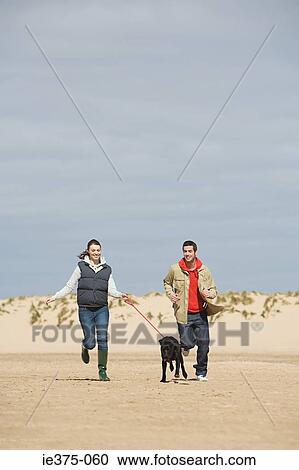 Couple running on beach with dog View Large Photo Image Stock Image - Couple running on beach with dog. Fotosearch