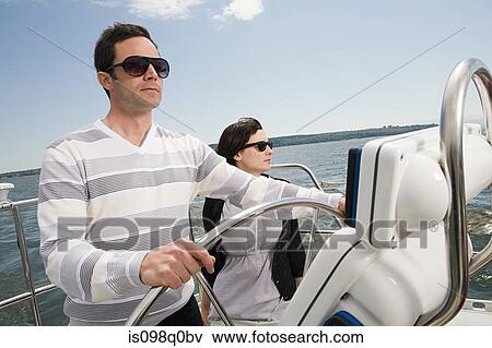 Stock Photo - Couple sailing a yacht. Fotosearch