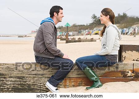 Couple sitting on a fence at the beach View Large Photo Image Stock Image - Couple sitting on a fence at the beach. Fotosearch