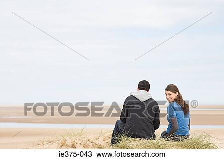 Stock Image - Couple sitting on an empty beach. Fotosearch