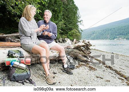 Stock Image - Couple sitting on log. Fotosearch