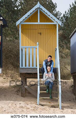 Picture - Couple sitting on steps of a beach hut. Fotosearch