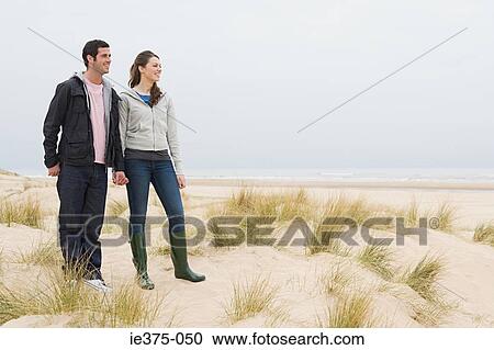 Stock Image - Couple standing on a sandy beach. Fotosearch