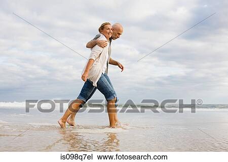 Stock Image - Couple walking in the sea. Fotosearch