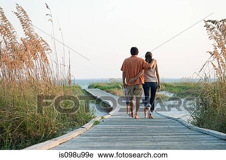 Couple walking on beach walkway View Large Photo Image Stock Image - Couple walking on beach walkway. Fotosearch