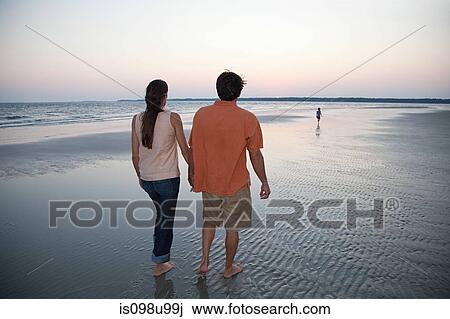 Couple walking on beach with daughter in distance View Large Photo Image Stock Image - Couple walking on beach with daughter in distance. Fotosearch
