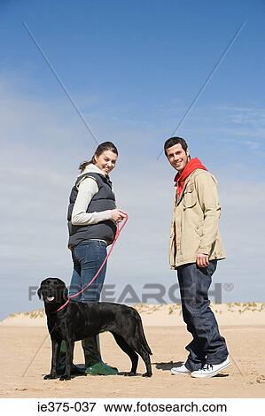 Stock Photo - Couple with pet dog on beach. Fotosearch