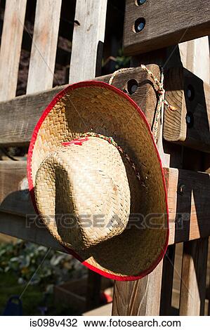 Stock Image - Cowboy hat hanging on wooden fence. Fotosearch
