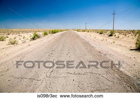 Stock Image - Cracked road stretching through the desert. Fotosearch
