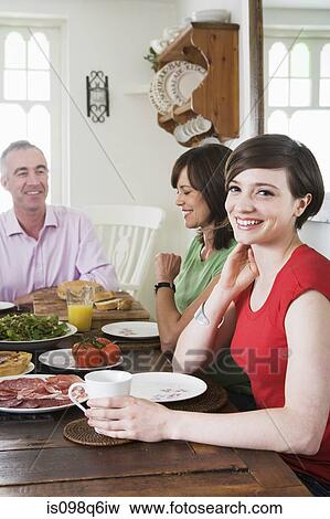 Daughter sat at dining table with her father and mother View Large Photo Image Stock Photo - Daughter sat at dining table with her father and mother. Fotosearch