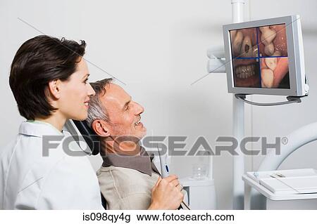 Dentist and patient looking at monitor View Large Photo Image Stock Image - Dentist and patient looking at monitor. Fotosearch