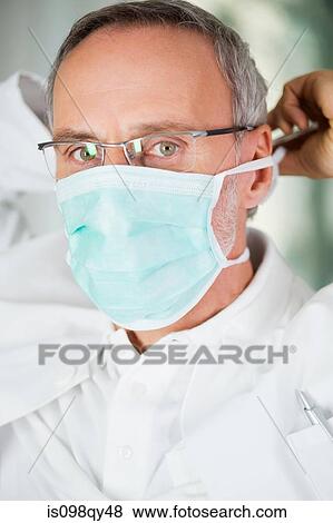 Dentist putting on mask View Large Photo Image Stock Photo - Dentist putting on mask. Fotosearch