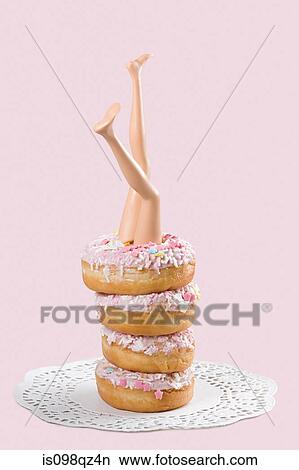 Picture - Doll legs in a stack of donuts. Fotosearch