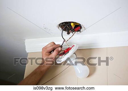 Stock Image - Electrician fixing lightbulb wiring. Fotosearch
