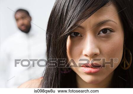Stock Photograph - Face of a woman with man in background. Fotosearch