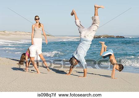 Stock Image - Family doing handstands on the beach. Fotosearch