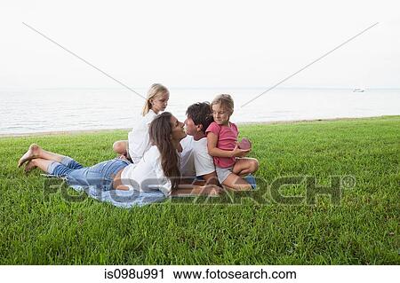 Family relaxing on grass by the sea View Large Photo Image Stock Image - Family relaxing on grass by the sea. Fotosearch