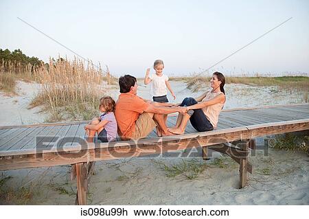Stock Image - Family sitting together on beach walkway. Fotosearch