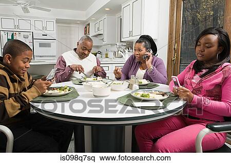 Stock Photography - Family using cell phones at the dinner table. Fotosearch