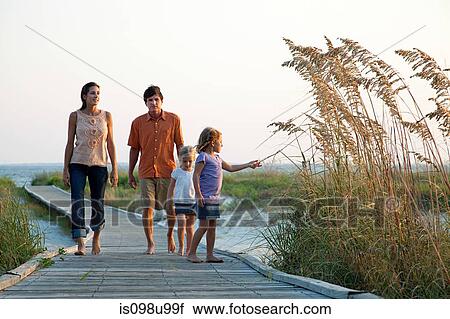 Stock Image - Family walking on beach walkway. Fotosearch