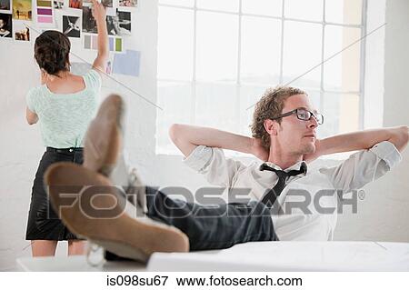 Stock Photo - Fashion designer sitting on chair, hands behind head. Fotosearch