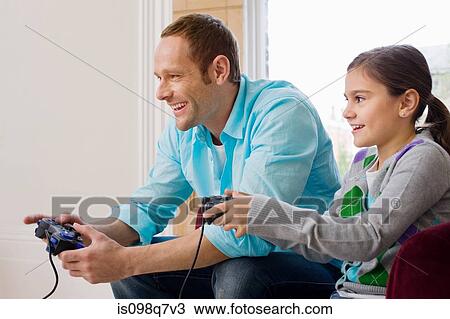 Stock Image - Father and daughter playing video game. Fotosearch