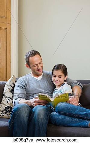 Stock Image - Father and daughter reading a book together. Fotosearch