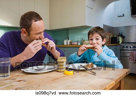 Stock Image - Father and son eating peanut butter sandwiches. Fotosearch