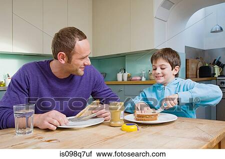 Stock Image - Father and son having peanut butter sandwiches. Fotosearch