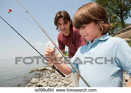 Stock Image - Father and son on beach with fishing rods. Fotosearch