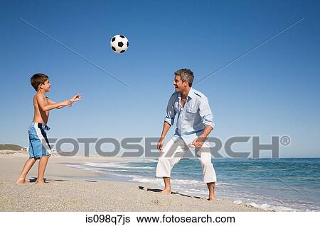 Father and son playing football by the sea View Large Photo Image Stock Photograph - Father and son playing football by the sea. Fotosearch