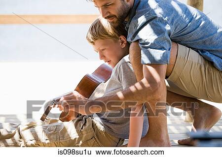 Stock Photograph - Father and son playing guitar. Fotosearch