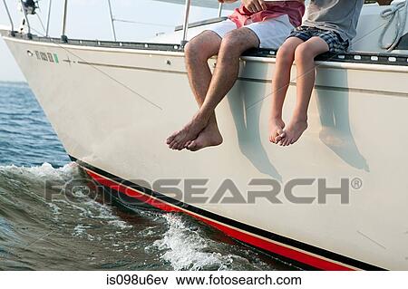 Father and son sitting on yacht, legs dangling View Large Photo Image Stock Photo - Father and son sitting on yacht, legs dangling. Fotosearch