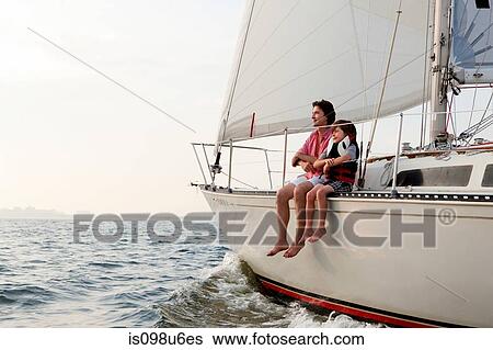 Stock Photograph - Father and son sitting on yacht. Fotosearch