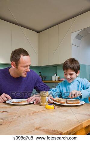 Stock Photo - Father and son spreading peanut butter on bread. Fotosearch