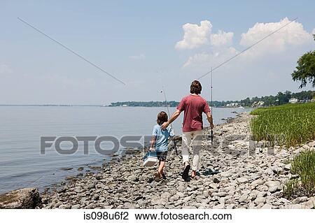 Father and son walking along beach with fishing rods View Large Photo Image Stock Image - Father and son walking along beach with fishing rods. Fotosearch